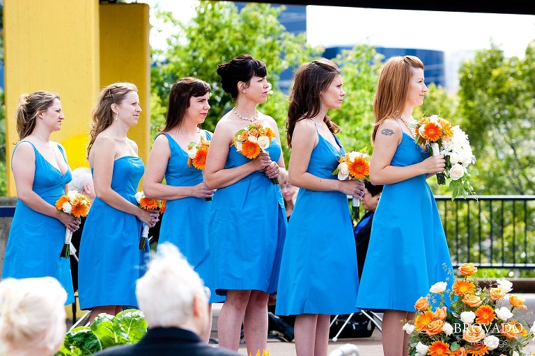 bridesmaids wearing blue dresses and holding orange bouquets