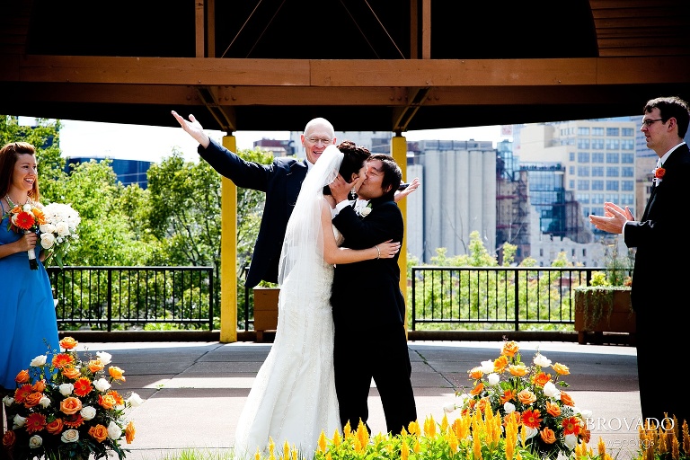 priest cheers as bride and groom share first kiss in front of minneapolis skyline