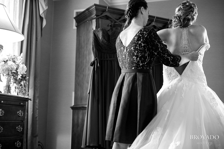 Bride gets help putting on her wedding dress