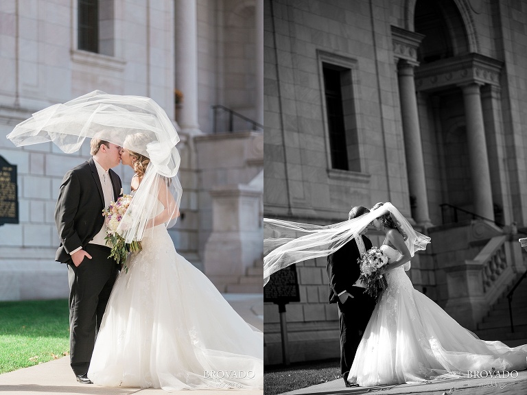 Bride and groom pose in front of historic st paul building with veil billowing