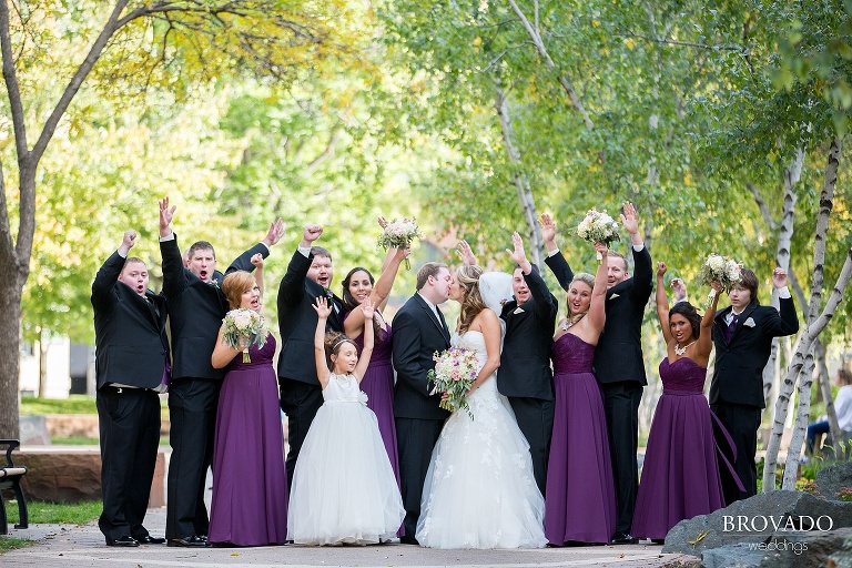 Wedding party cheers as bride and groom kiss