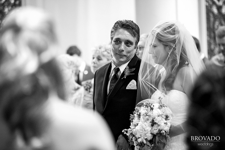 Bride walks down the aisle, veil covering her face