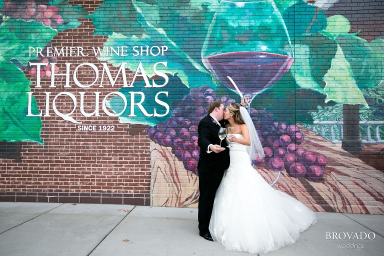 Bride and groom kiss in front of a wine and liquor store