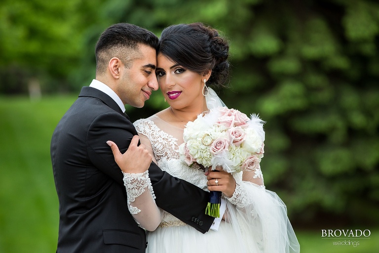 Groom embraces bride as she looks at the camera