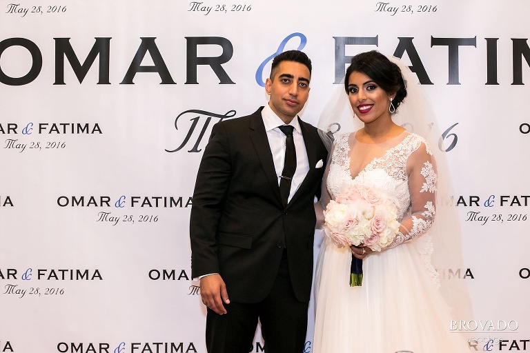 Bride and groom in front of photo backdrop with their names