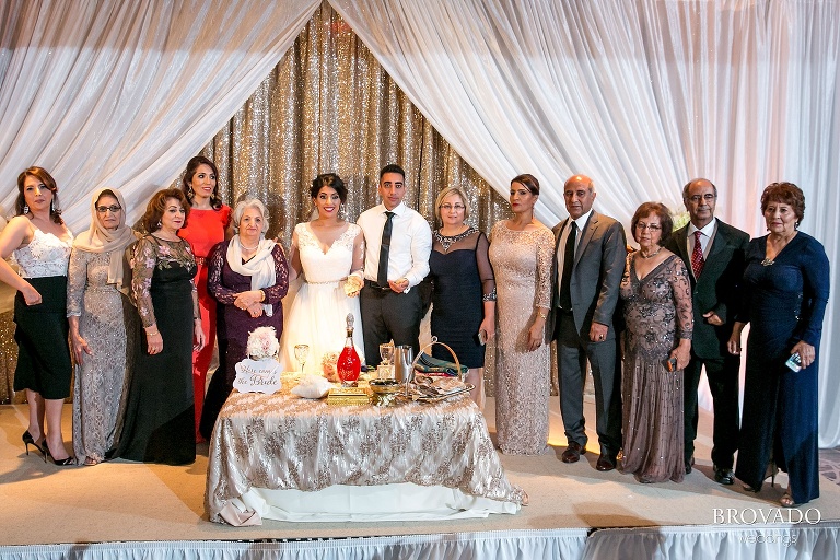 Family gathers together around bride and groom at wedding reception