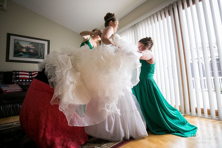Heidi's bridesmaids putting on her wedding dress
