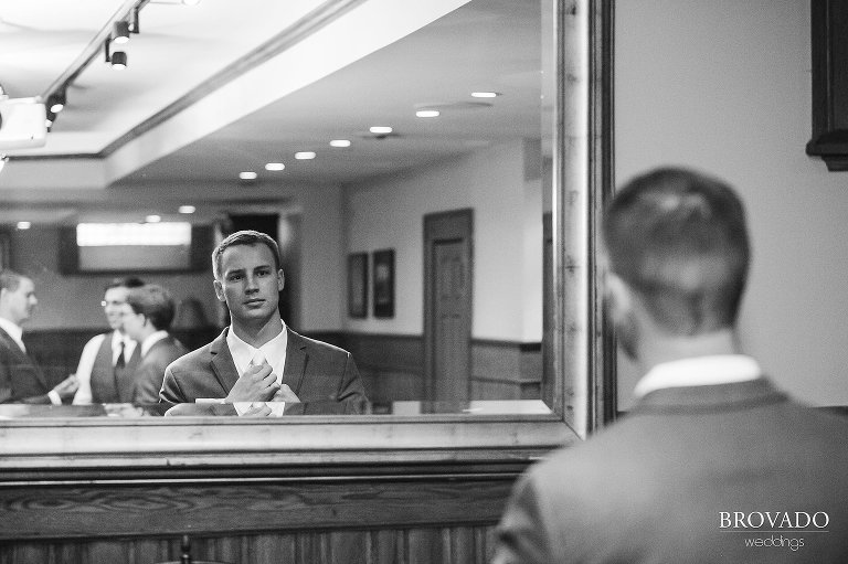 Groom Aaron fixing his tie in the mirror