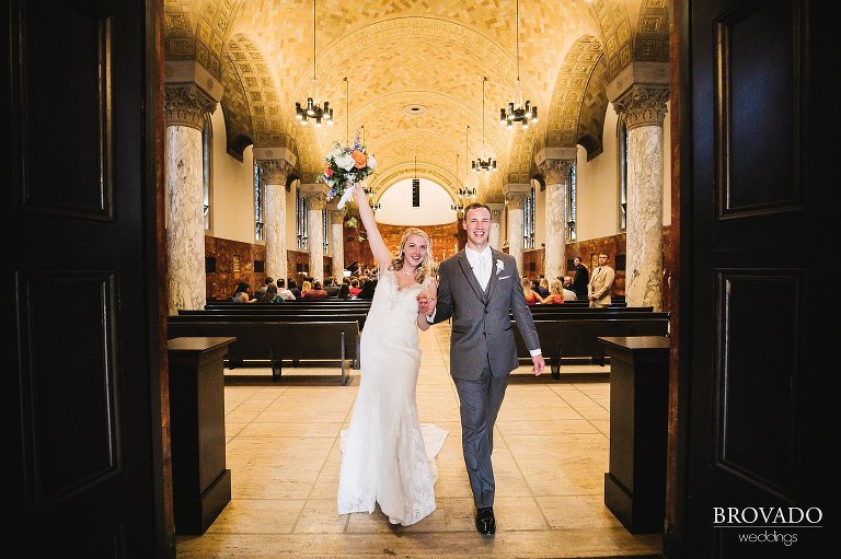 Bride and groom cheering while leaving church