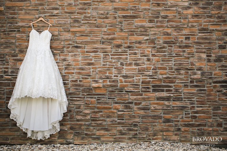 Sally's wedding dress hanging against a brick wall