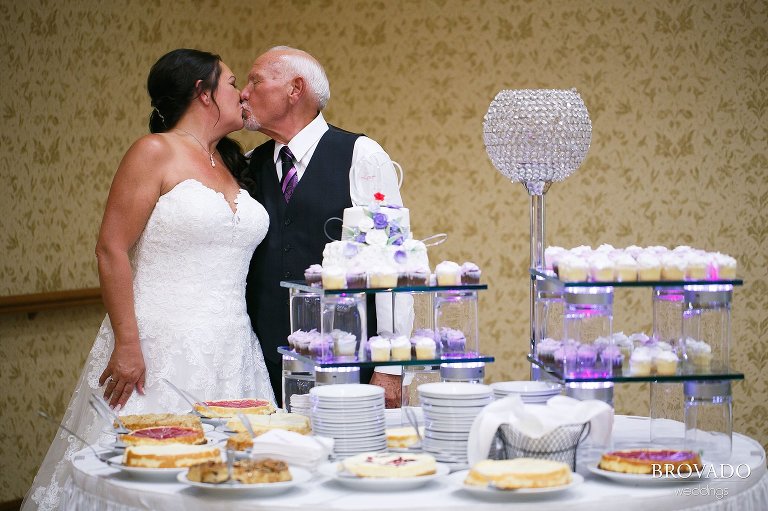Sally and Daniel kissing in front of wedding desserts