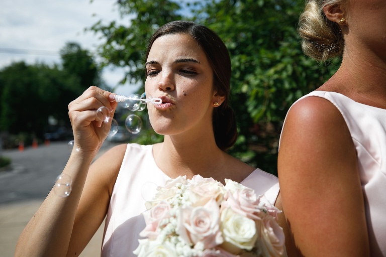 Bridesmaid blowing bubble for church exit