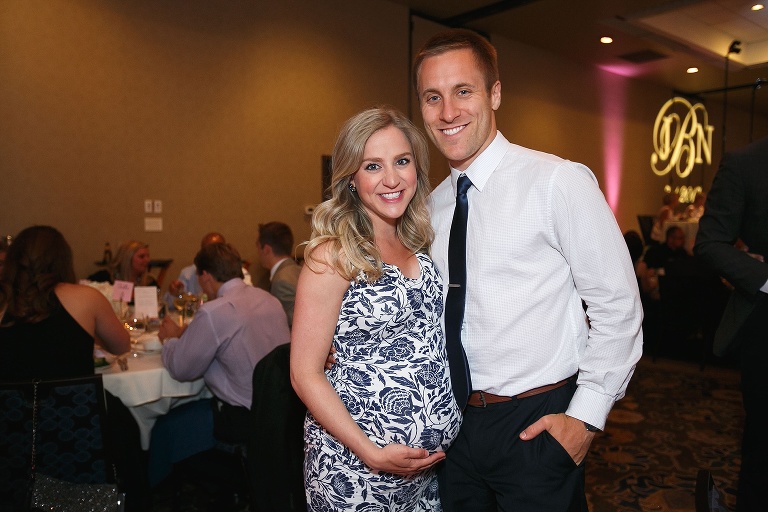 Pregnant couple posing at wedding reception