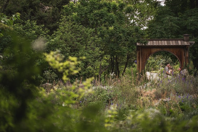 Engaged couple kissing under conservatory arch