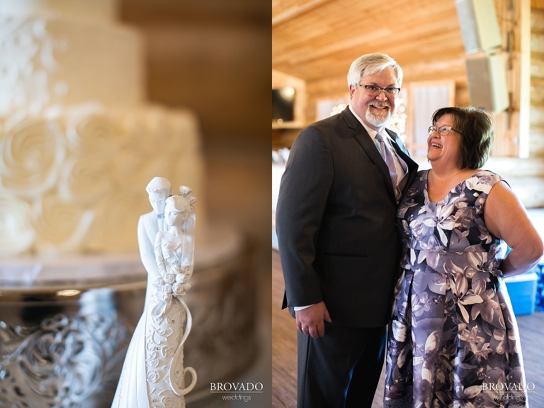 Mother and father of the bride posed next to wedding cake topper