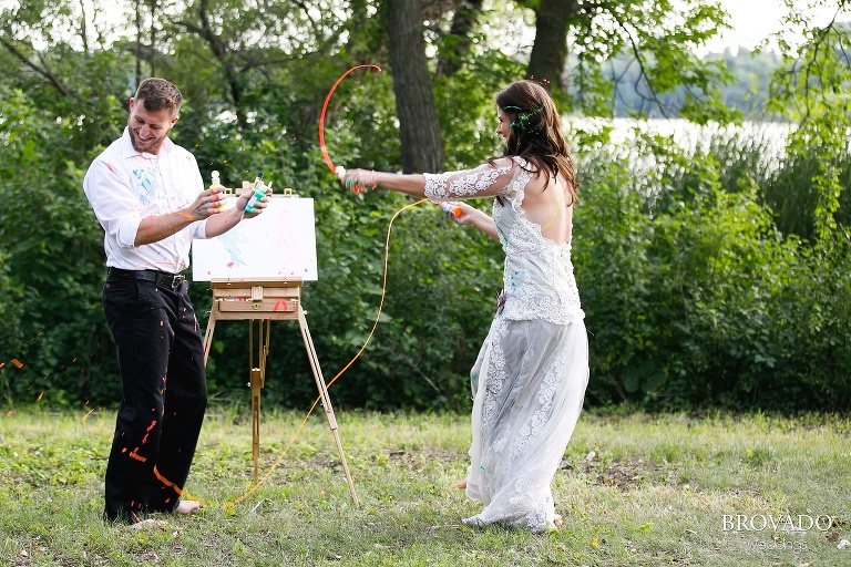 Married couple throwing paint on wedding dress