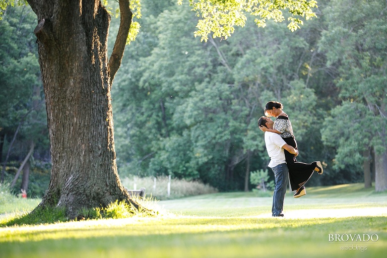 Engaged couple kissing next to a tree