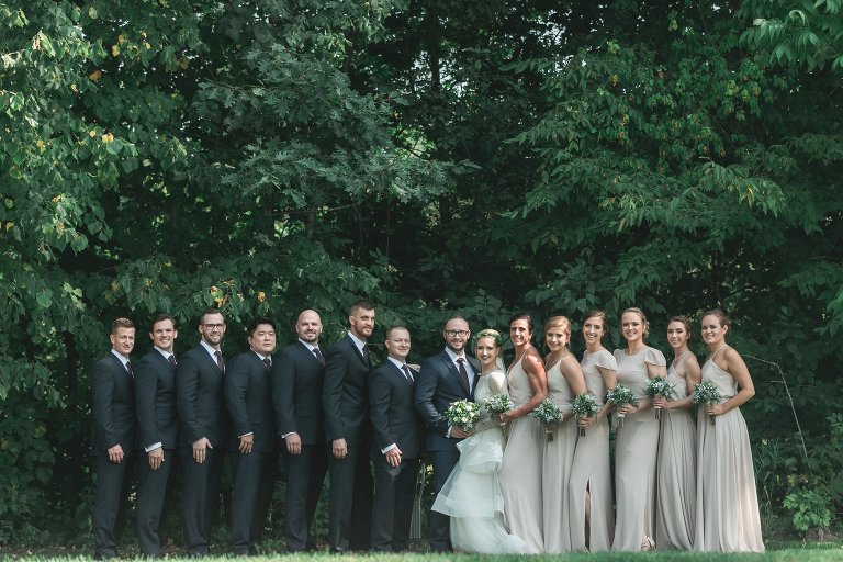 Bride and groom with wedding party in dark grey suits and tan dresses