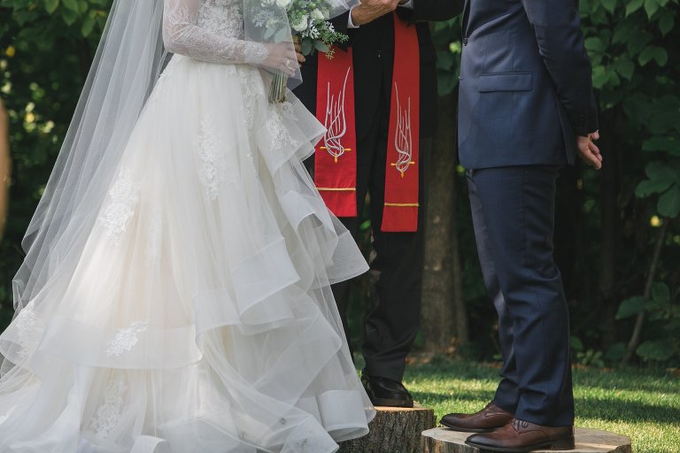 Bride and groom standing on wood slices at wedding ceremony