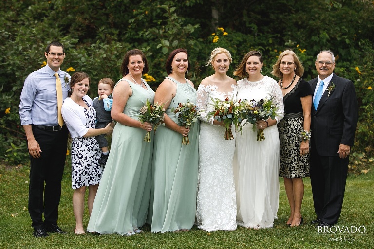 Two brides posing with their family