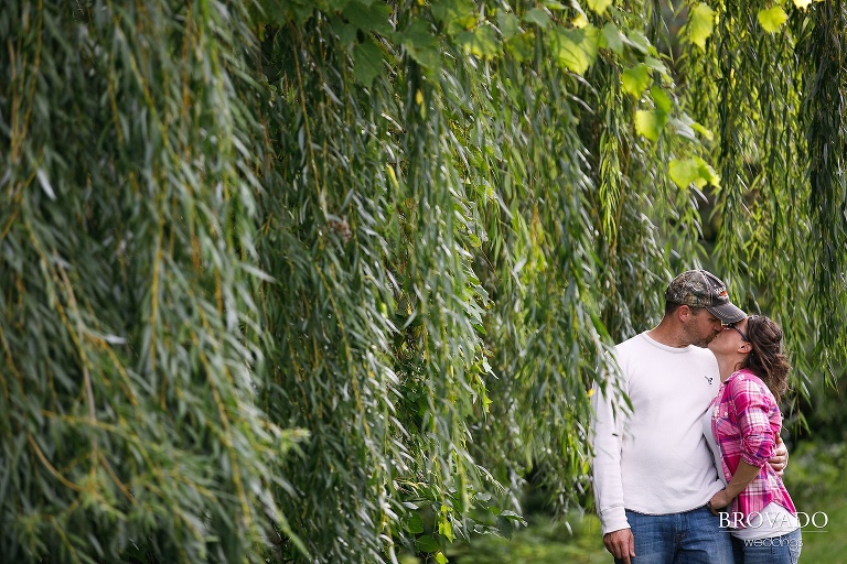 Kelly and Robert kissing in front of trees