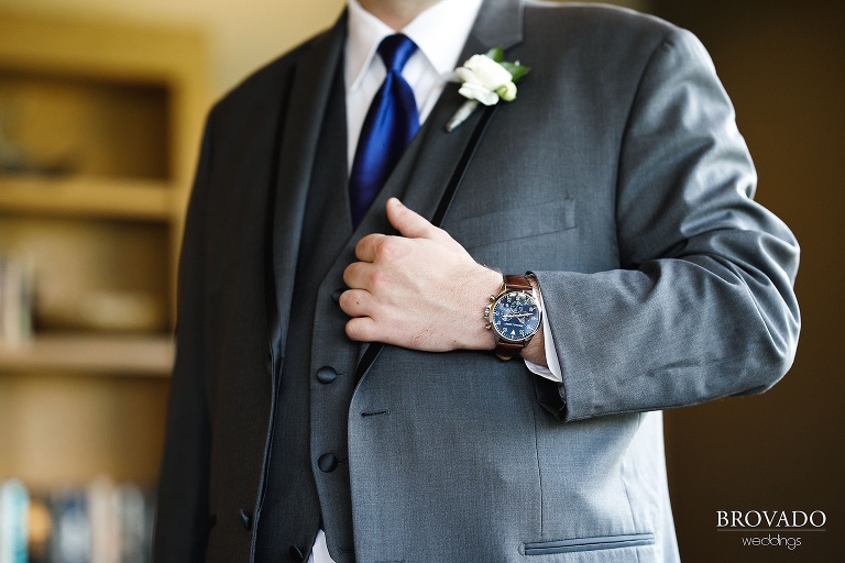 Closeup of Tom's brown leather watch and grey suit