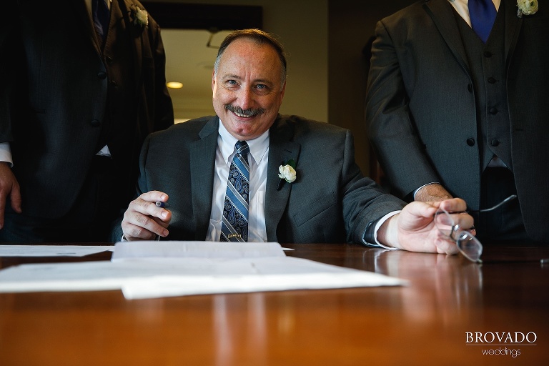 Tom's father and officiant signing marriage license 