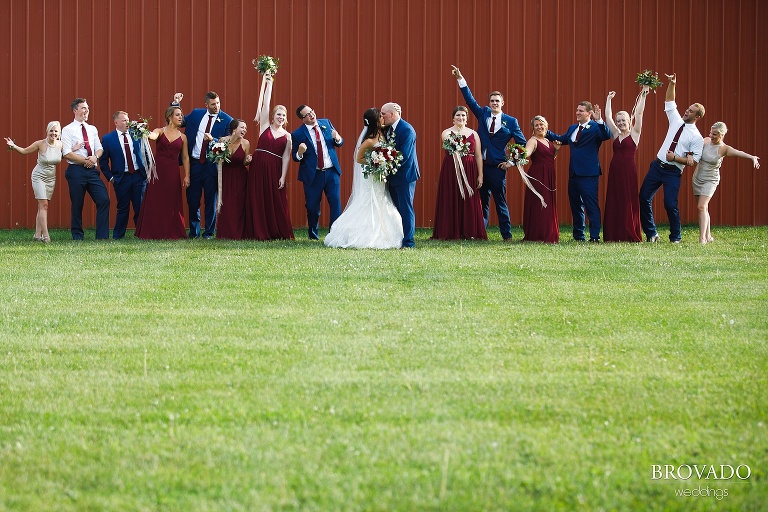 Brenna and Derek's wedding party posing against a red wall