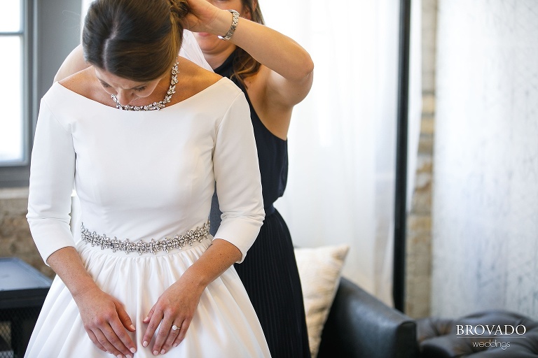 Bride hannah putting on her wedding day necklace