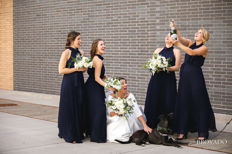 Bridesmaids popping champagne while Hannah pets a dog