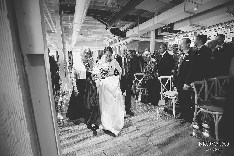 Hannah and her parents laughing while walking down the aisle