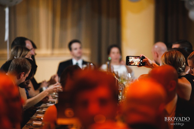 Bridesmaid taking a photo of the bride and groom at wedding reception