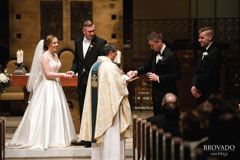 Best man passing wedding rings to priest at Megan and Ben's wedding