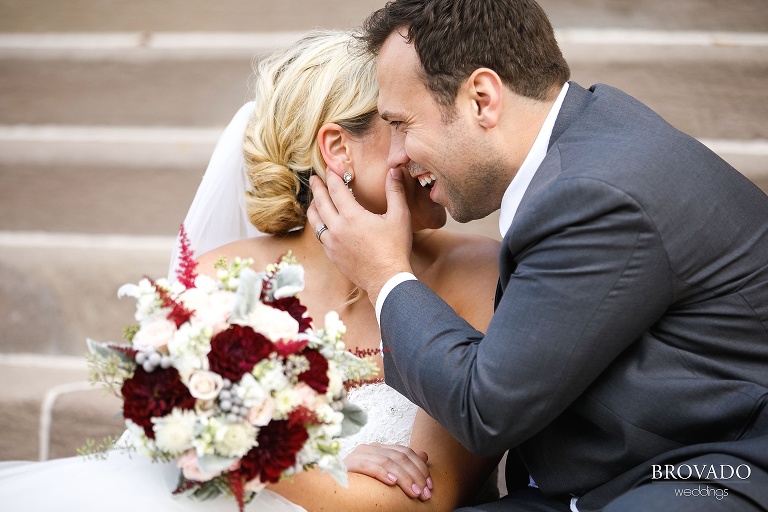 Joe laughing while bride Rachel whispers in his ear
