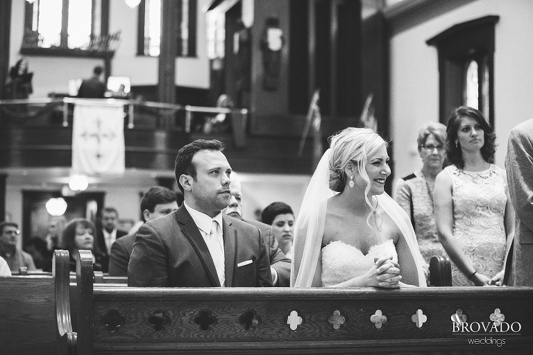 Rachel and Joe smiling from their pew in black and white