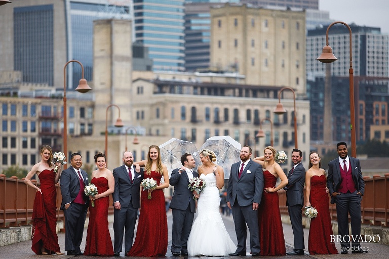 Rachel and Joe's wedding party posing with umbrellas on the stone arch bridge