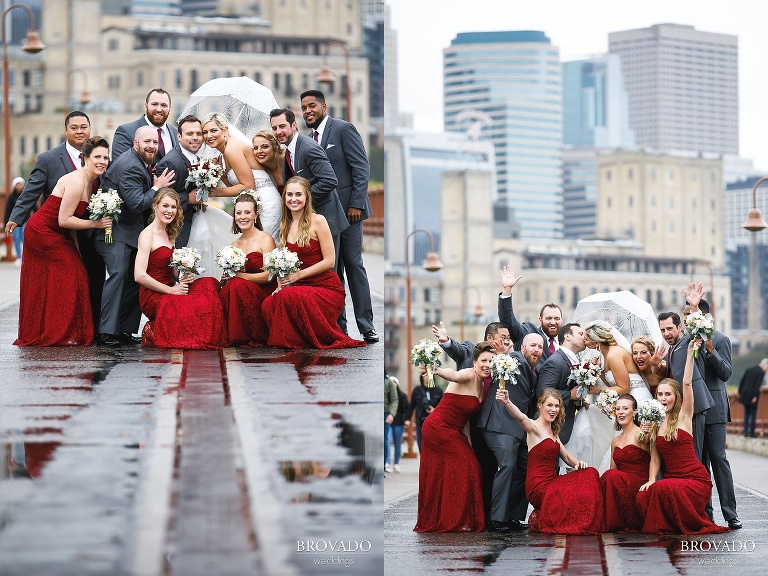 Rachel and Joe posing with their wedding party in the rain on the stone arch bridge