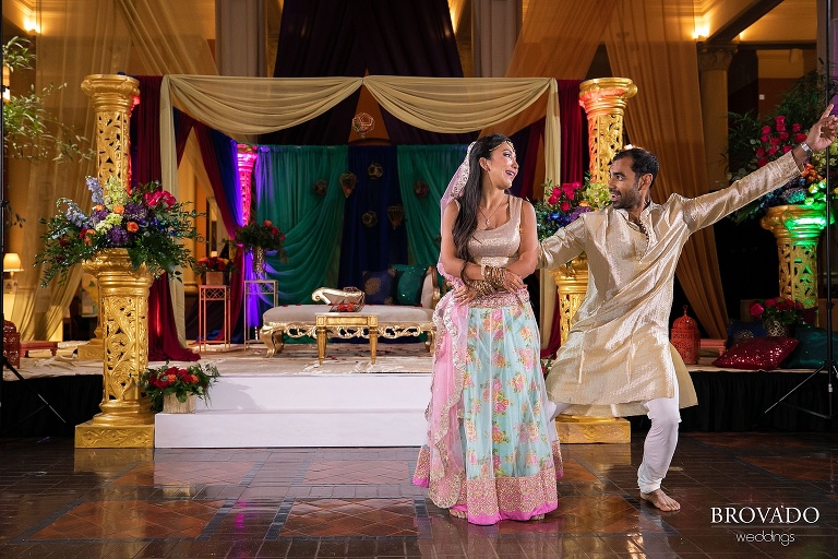Bride and groom dancing in gold reception outfits