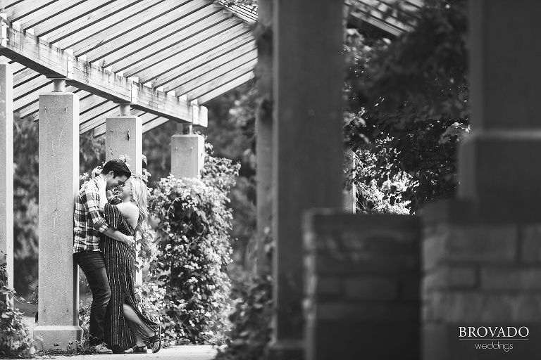 Black and white photo of couple kissing under archway