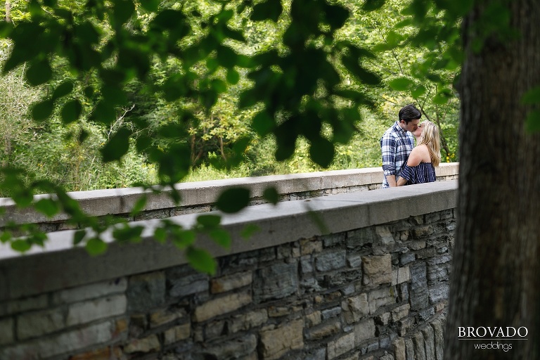 Engaged couple kissing on bridge 