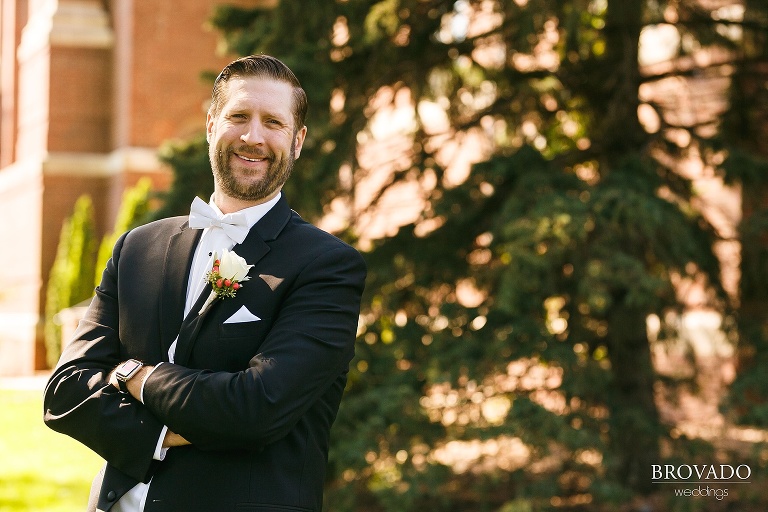 Groom Matthew laughing with his arms crossed
