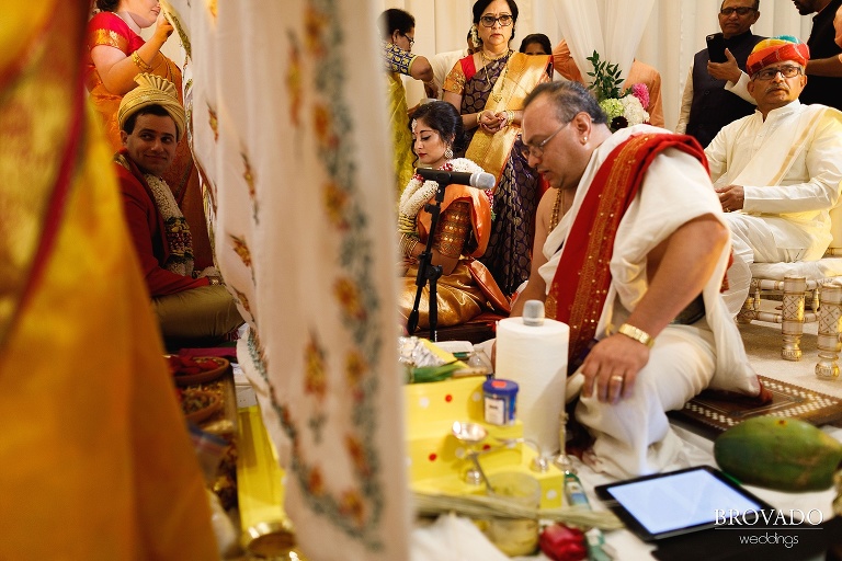 Sruti and Ethan sitting on opposite sides of cloth during hindu ceremony