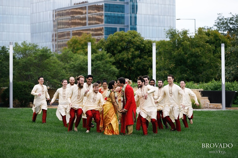 Wedding party running towards kissing bride and groom