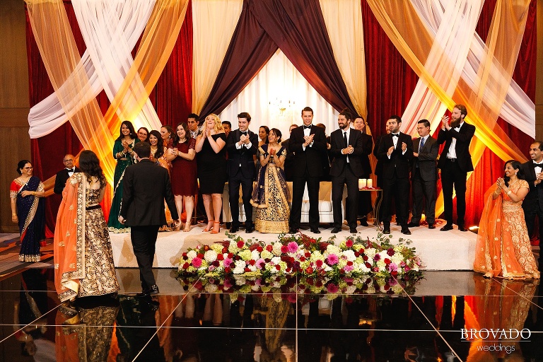 Wedding party clapping as bride and groom enter reception