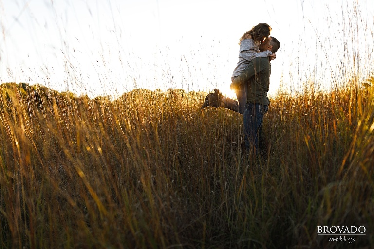 backlit engagement photo in a field during golden hour