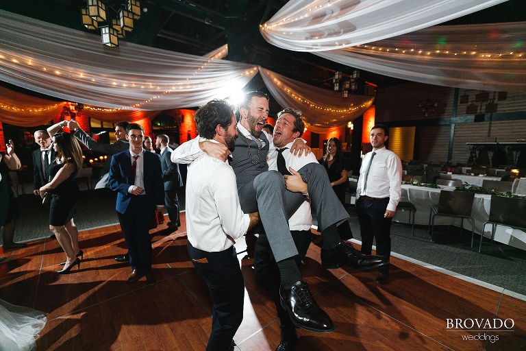 groomsmen picking up the groom while dancing