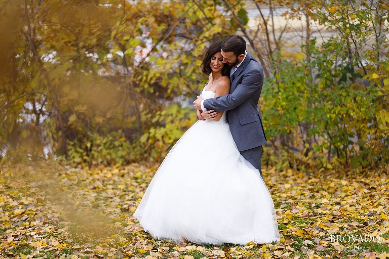 Bride and groom embracing in fall leaves
