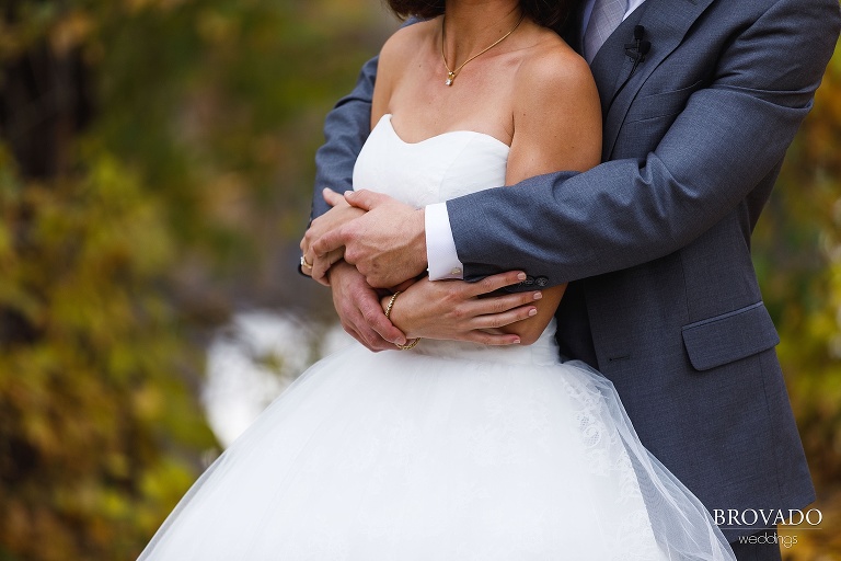 close up of groom's arms wrapped around bride