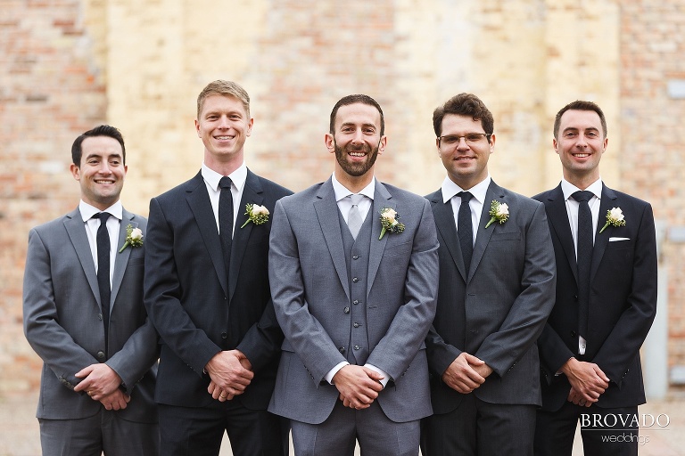 Groomsmen standing against a brick wall