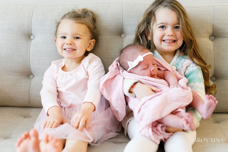 Two girls holding their newborn sister